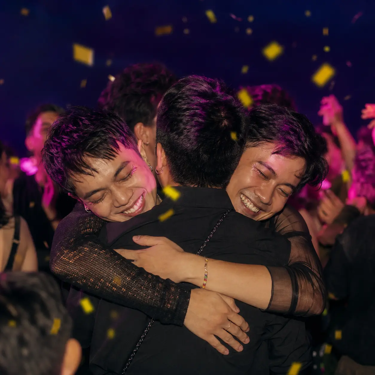 Adult queer friends hugging at a community celebration
