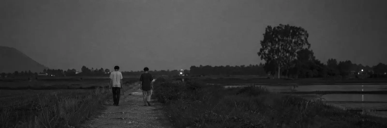 Panoramic black and white rural Vietnam scene with anonymized adult young men