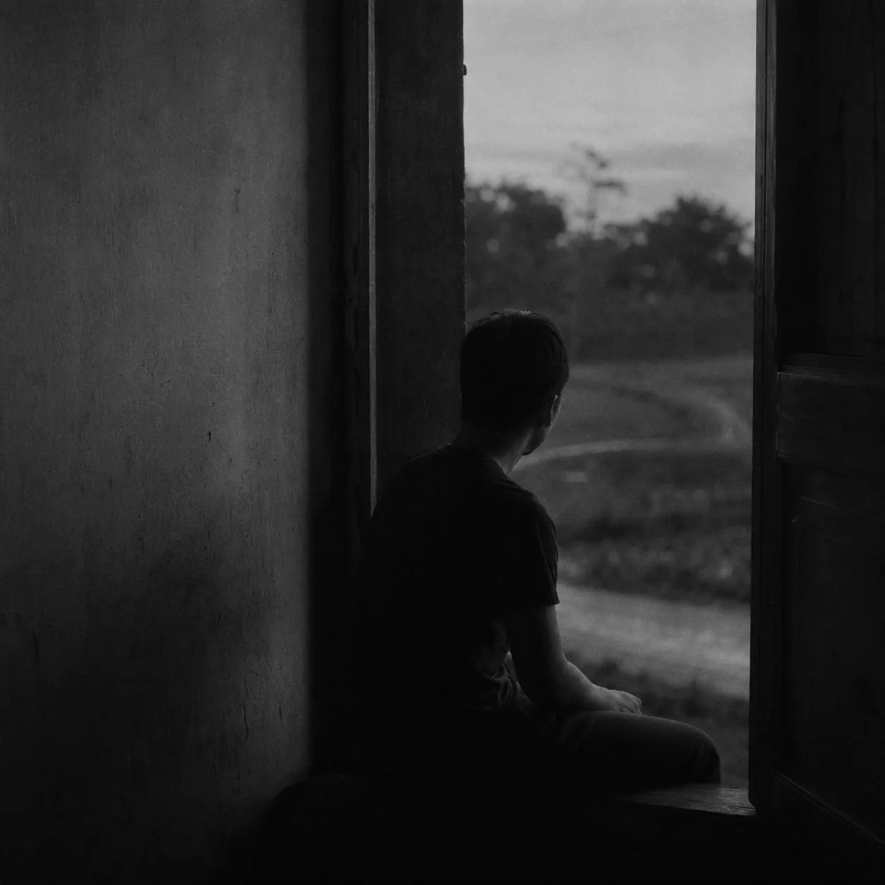 Black and white doorway portrait of an anonymized adult young man